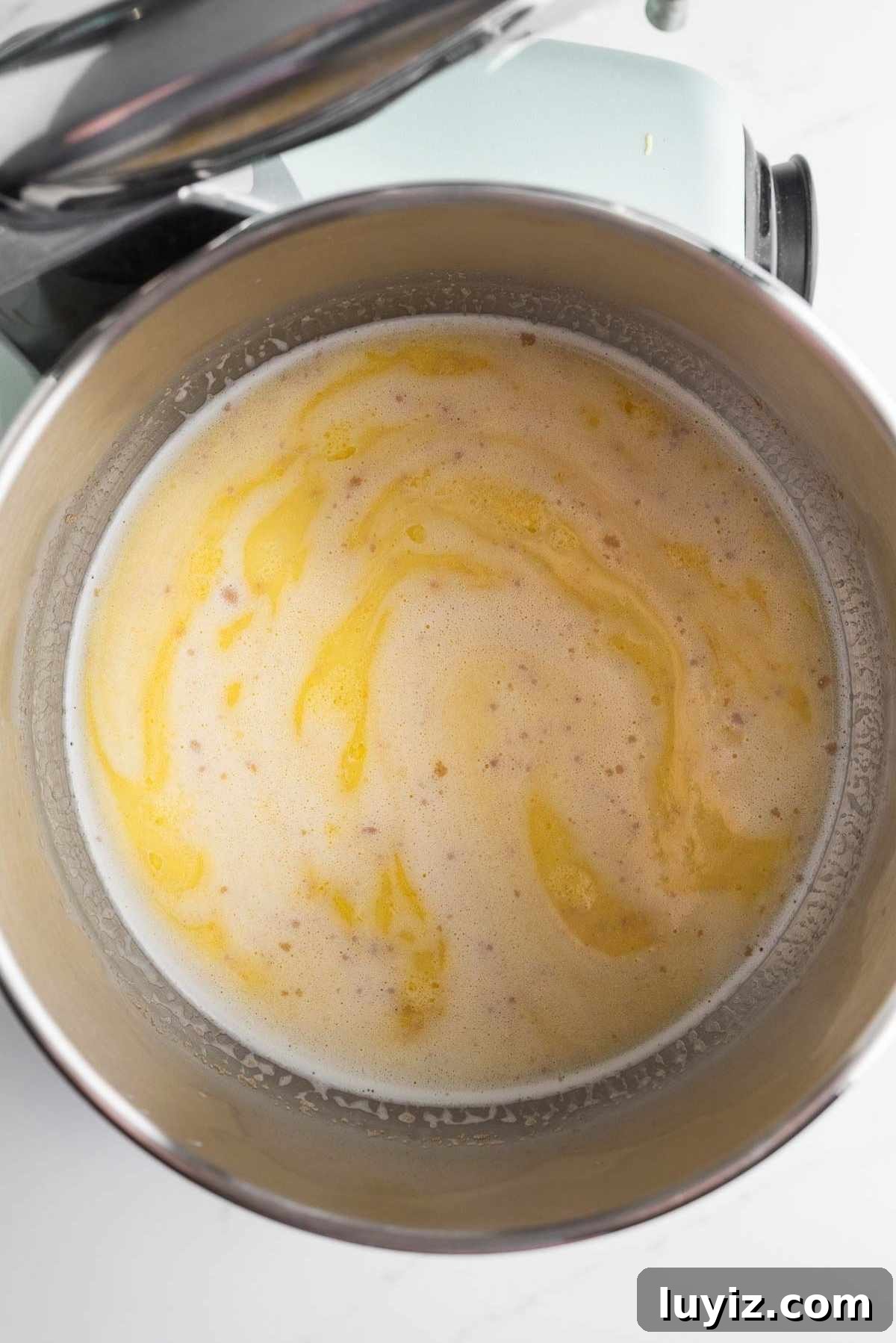 Yeast, egg mixture, and warmed milk whisked together in a mixing bowl.